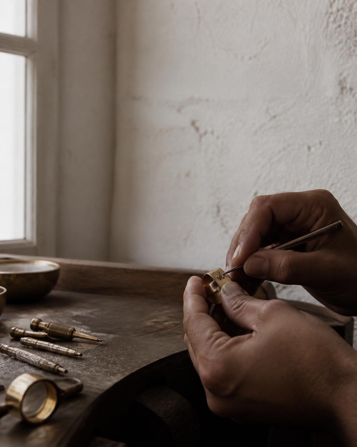 A stone being set into a brass setting